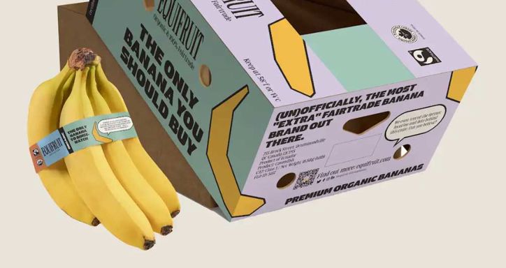 A cardboard box branded with "Equifruit" holds bananas, with a bunch placed beside it.