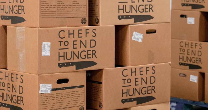 Two pallets loaded with cardboard boxes with the words Chefs to end Hunger printed on each box